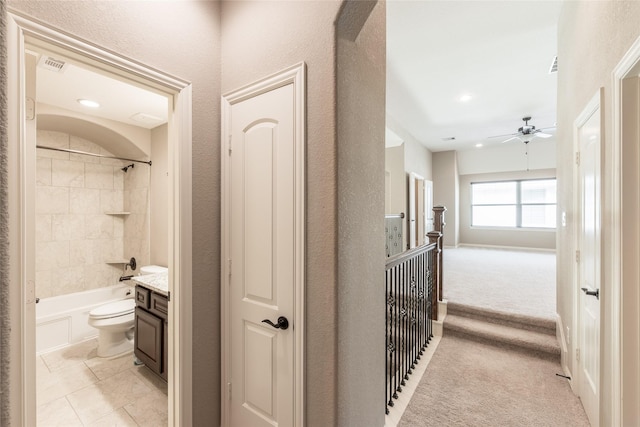 hallway with visible vents, light carpet, and a textured wall