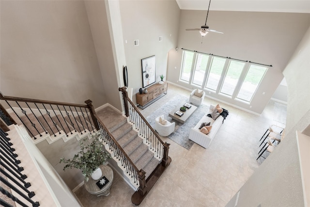 living room with a ceiling fan, visible vents, baseboards, a high ceiling, and tile patterned floors