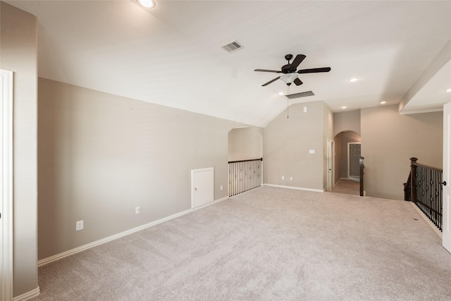 interior space with a ceiling fan, visible vents, carpet floors, arched walkways, and vaulted ceiling