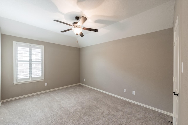 empty room featuring baseboards, carpet, ceiling fan, and vaulted ceiling