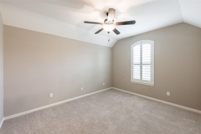 carpeted spare room featuring baseboards, a ceiling fan, and vaulted ceiling