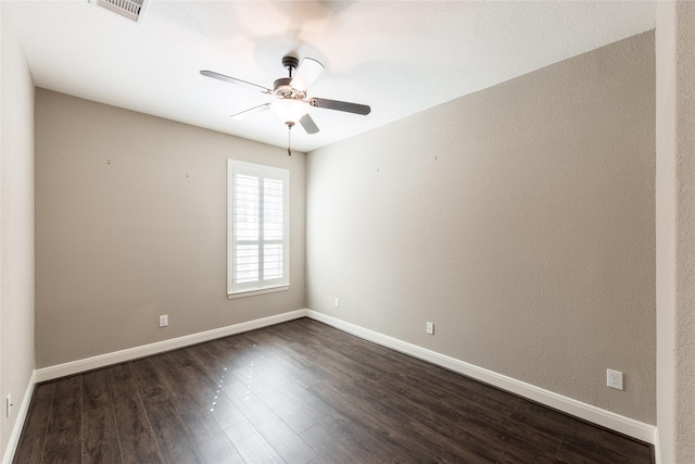 empty room featuring dark wood-style floors, visible vents, ceiling fan, and baseboards