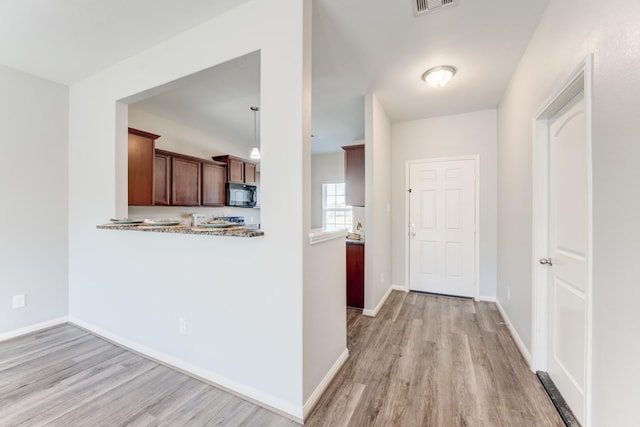 kitchen featuring baseboards, light wood-type flooring, and black microwave