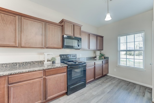 kitchen with black appliances, light wood-style flooring, light stone countertops, and baseboards