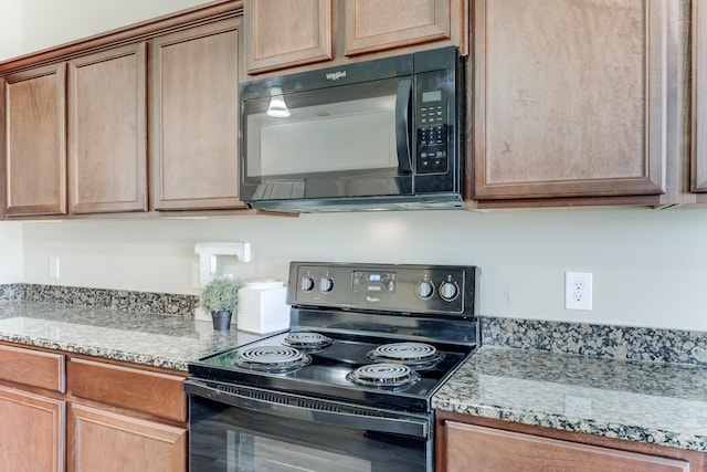 kitchen with light stone counters and black appliances