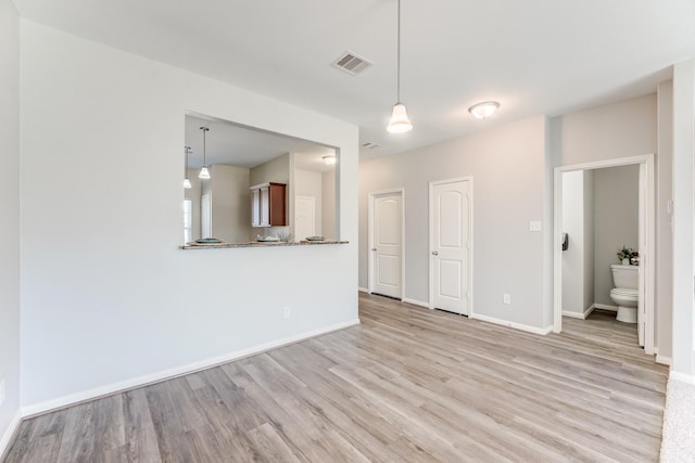 unfurnished living room featuring visible vents, light wood-type flooring, and baseboards