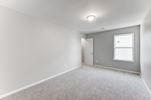 carpeted spare room with visible vents and baseboards