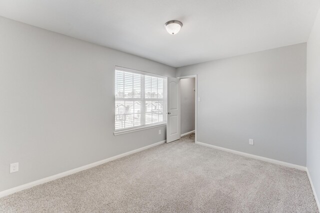 empty room featuring light colored carpet and baseboards