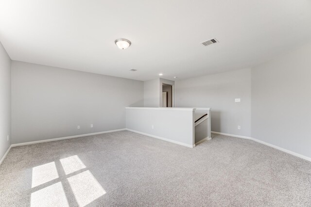 spare room featuring visible vents, baseboards, and light carpet