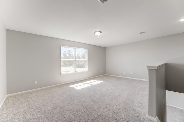 carpeted spare room featuring visible vents and baseboards