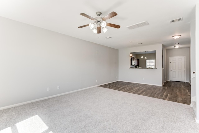 unfurnished living room with visible vents, dark carpet, baseboards, and a ceiling fan