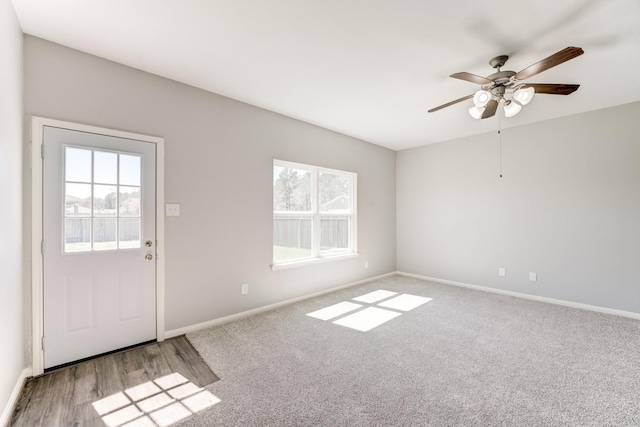 carpeted spare room with ceiling fan and baseboards