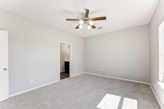 carpeted spare room featuring visible vents, baseboards, and a ceiling fan