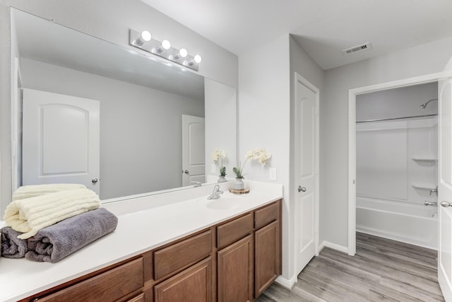 full bathroom with visible vents,  shower combination, wood finished floors, and vanity