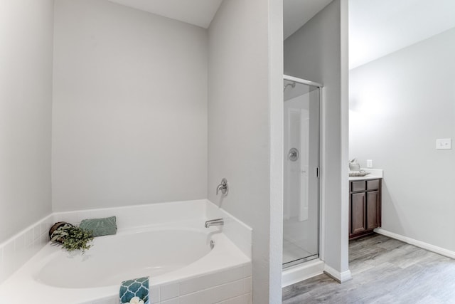 bathroom with a shower stall, baseboards, a garden tub, wood finished floors, and vanity