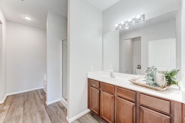 bathroom with vanity, a shower stall, wood finished floors, and baseboards