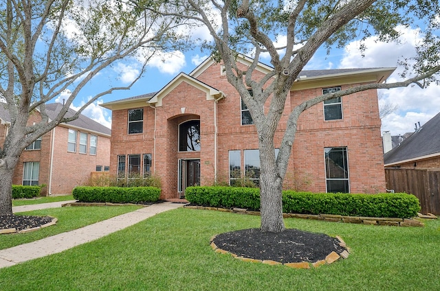 traditional-style home with brick siding, a front yard, and fence