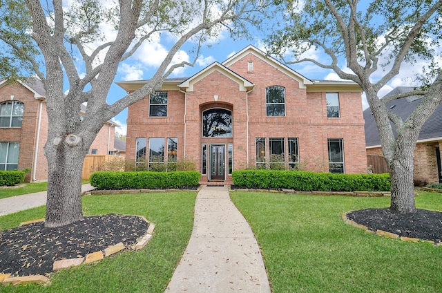 traditional home featuring brick siding, a front lawn, and fence