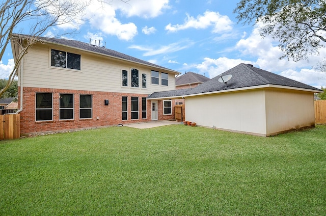 back of property with brick siding, a lawn, a patio, and fence