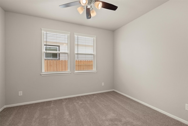 carpeted spare room with a ceiling fan and baseboards