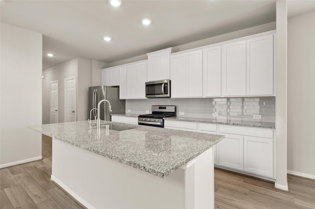 kitchen featuring a sink, a kitchen island with sink, white cabinetry, and stainless steel appliances