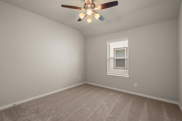 empty room with lofted ceiling, carpet flooring, a ceiling fan, and baseboards