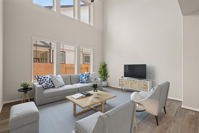 living room with baseboards, a high ceiling, and wood finished floors