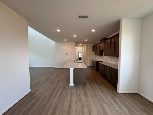 19127 Hazel Firs Ln, Magnolia, TX 77355 - kitchen featuring dark brown cabinetry, light wood-style floors, baseboards, a kitchen island with sink, and recessed lighting