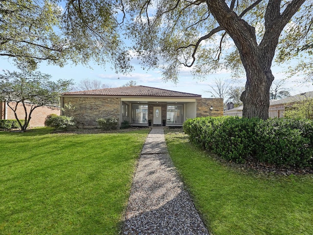 view of front of house featuring a front yard, a tiled roof, and stone siding