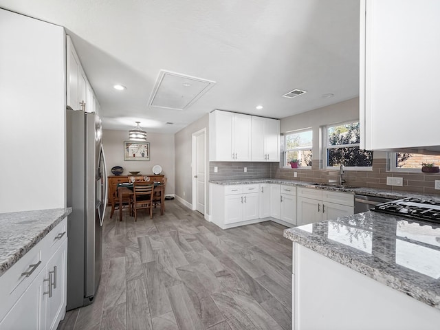 kitchen featuring tasteful backsplash, visible vents, light stone counters, appliances with stainless steel finishes, and a sink