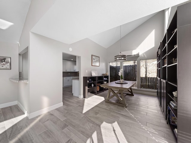 dining room featuring baseboards and high vaulted ceiling