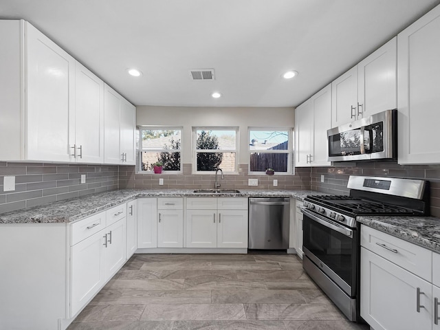 kitchen with a sink, visible vents, appliances with stainless steel finishes, and decorative backsplash