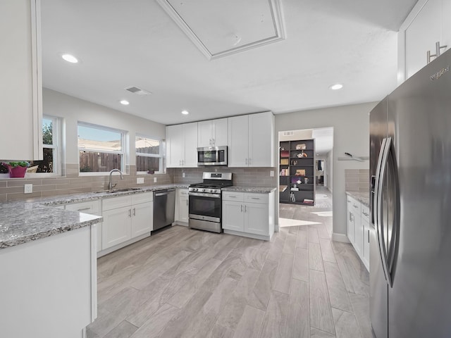 kitchen with light stone counters, visible vents, appliances with stainless steel finishes, white cabinetry, and tasteful backsplash