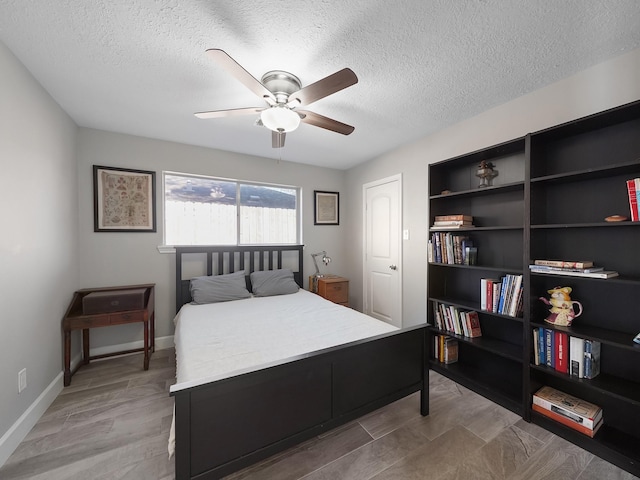 bedroom featuring light wood-style flooring, a textured ceiling, baseboards, and a ceiling fan