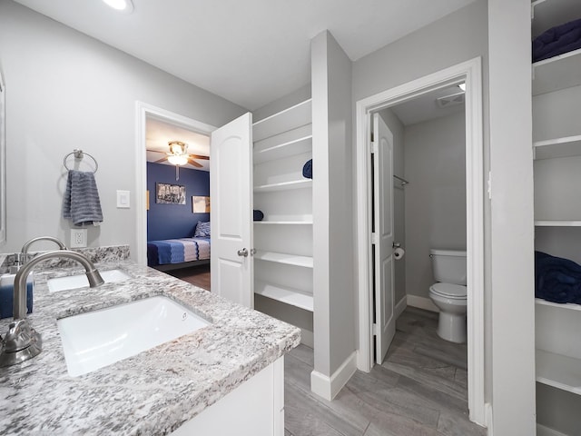 bathroom with visible vents, baseboards, toilet, vanity, and ensuite bath