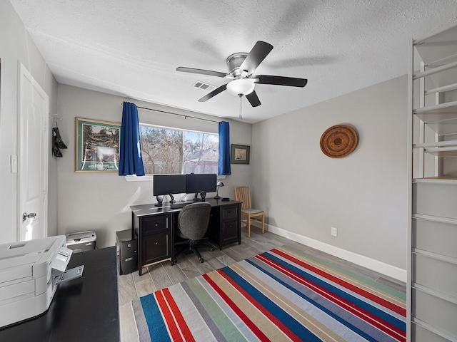 office space featuring visible vents, baseboards, wood tiled floor, a textured ceiling, and a ceiling fan