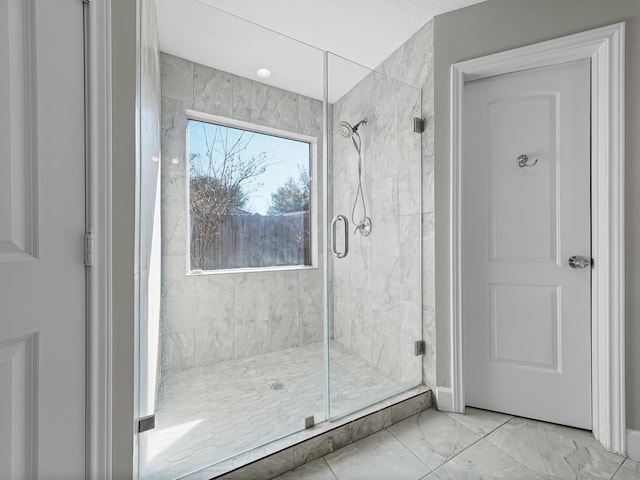 bathroom featuring a shower stall and marble finish floor