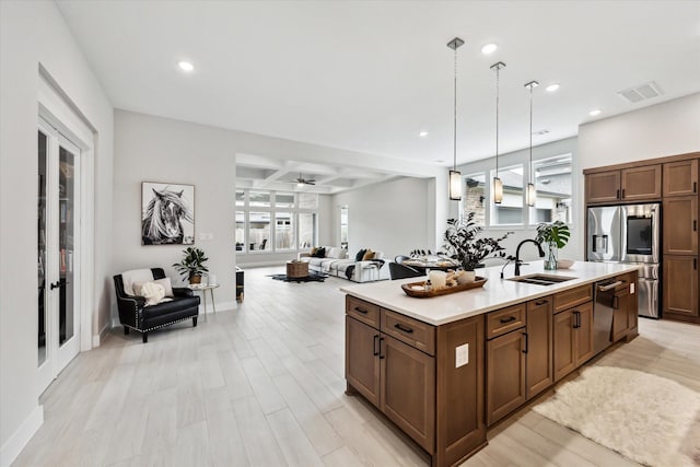 kitchen featuring visible vents, open floor plan, a center island with sink, stainless steel appliances, and a sink