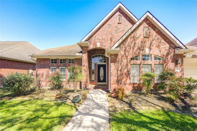 view of front of house featuring a front yard, brick siding, and a shingled roof