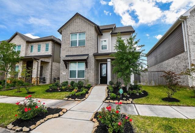 craftsman house with brick siding, a front yard, and fence