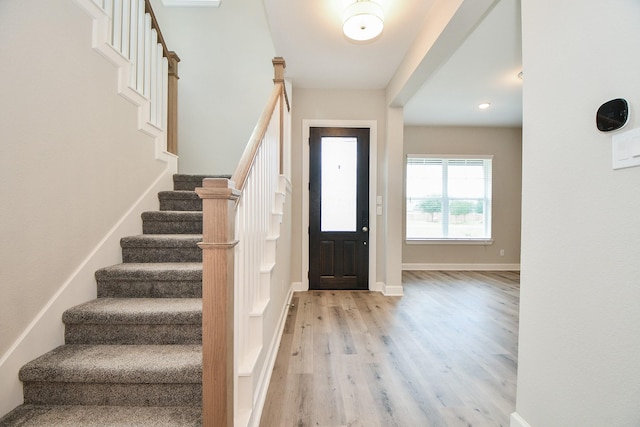 entrance foyer featuring baseboards, light wood-style floors, and stairs