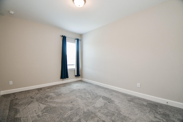 carpeted empty room featuring baseboards