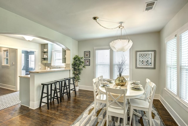 dining space featuring a wealth of natural light, baseboards, visible vents, and dark wood-style flooring