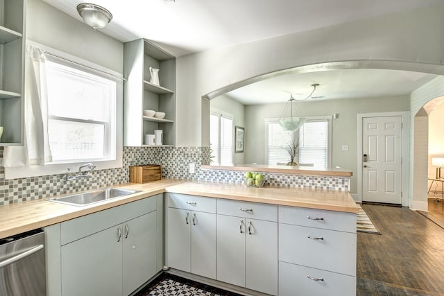 kitchen with open shelves, dishwasher, arched walkways, wood counters, and a sink