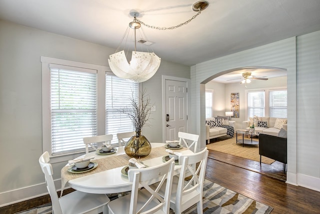 dining space featuring visible vents, wood finished floors, arched walkways, baseboards, and ceiling fan