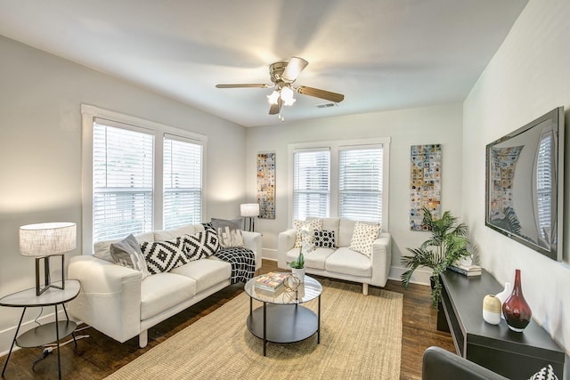 living area featuring ceiling fan, visible vents, baseboards, and dark wood-style floors