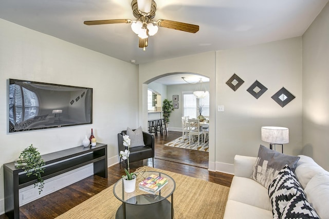 living room with baseboards, arched walkways, wood finished floors, and a ceiling fan