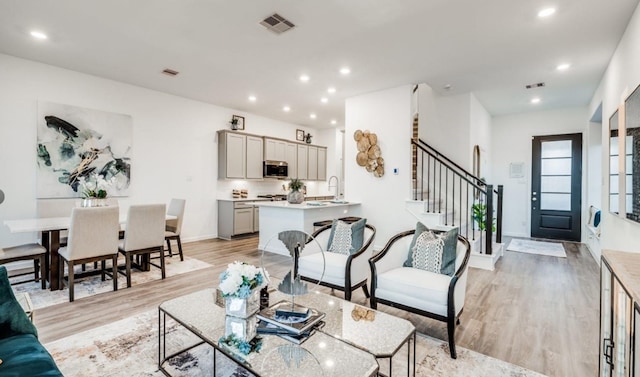 living room with recessed lighting, visible vents, light wood-style floors, and stairway