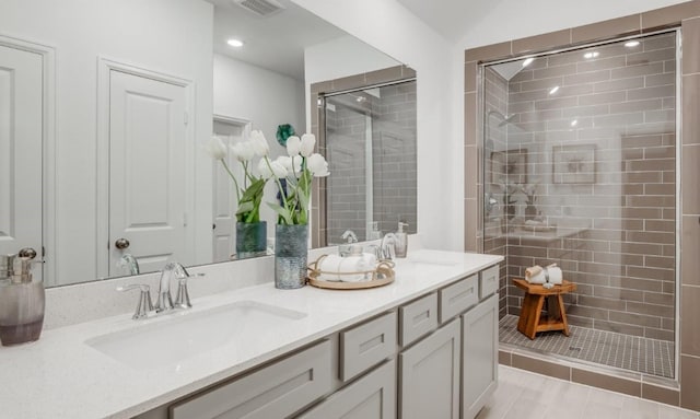 bathroom with double vanity, visible vents, a shower stall, and a sink