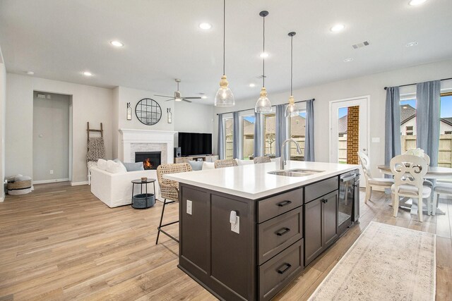 kitchen featuring visible vents, light wood-type flooring, a lit fireplace, and a sink